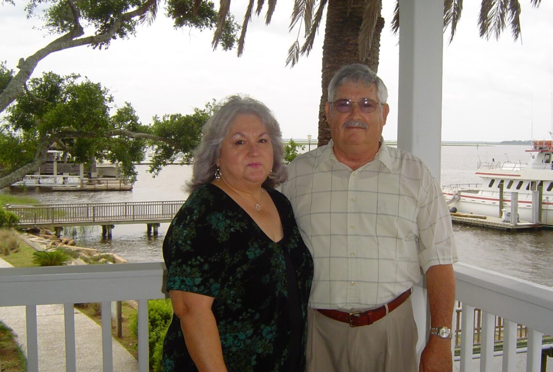 Gray-haired couple posing at harbor.